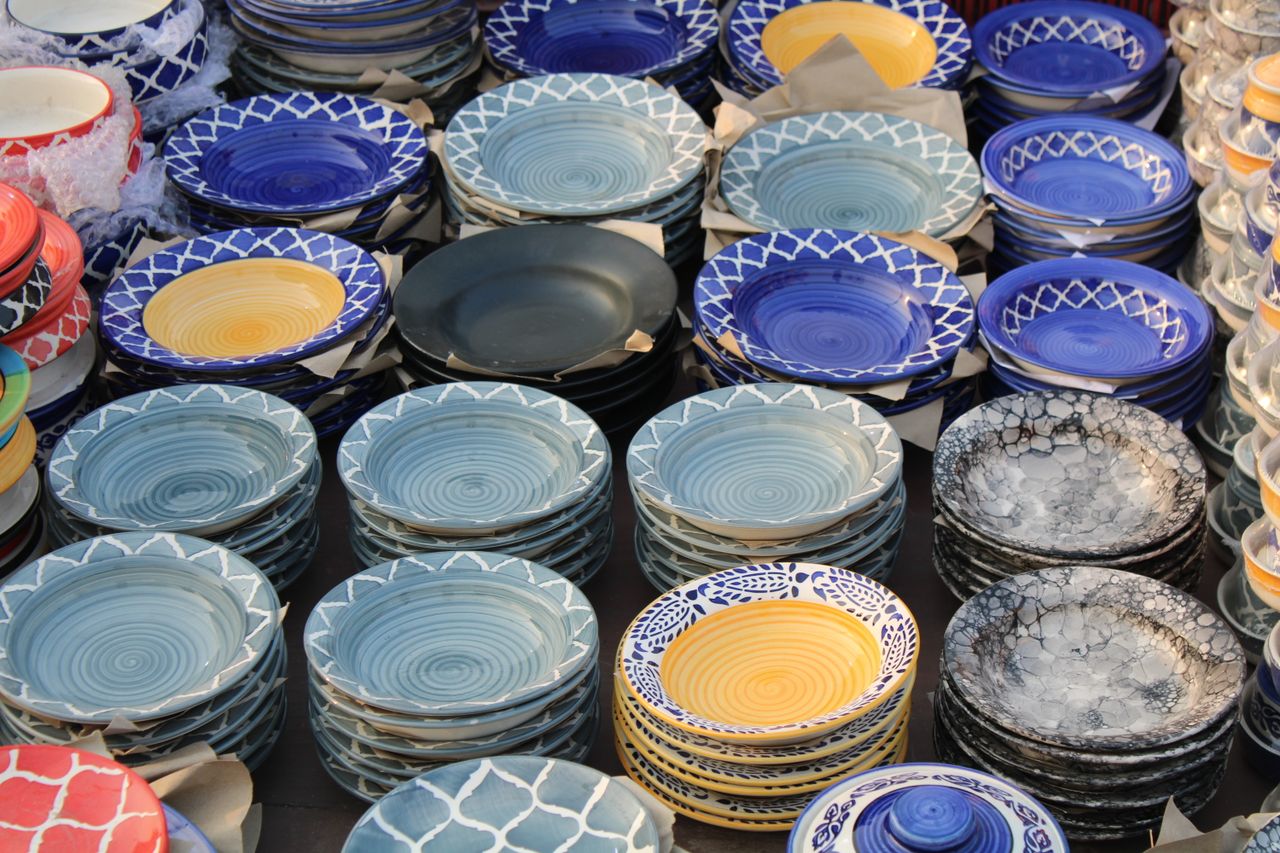Home Brightly colored ceramic plates stacked on display, showcasing intricate designs.