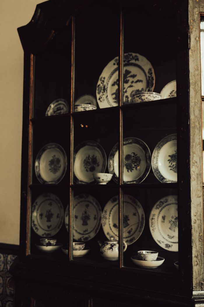 Services A vintage wooden cabinet displaying classic decorative china plates in a rustic setting.