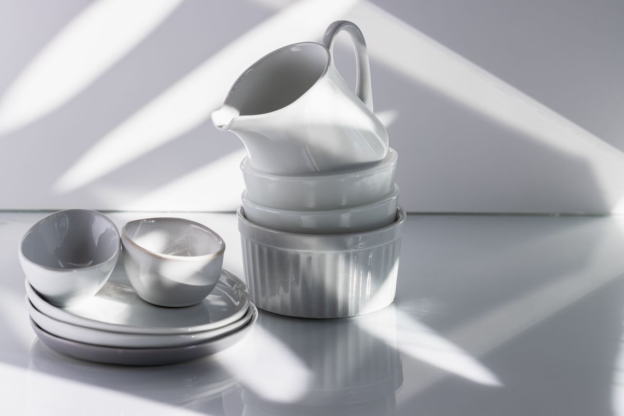 Home Elegant arrangement of white porcelain tableware with dramatic studio lighting and shadows.